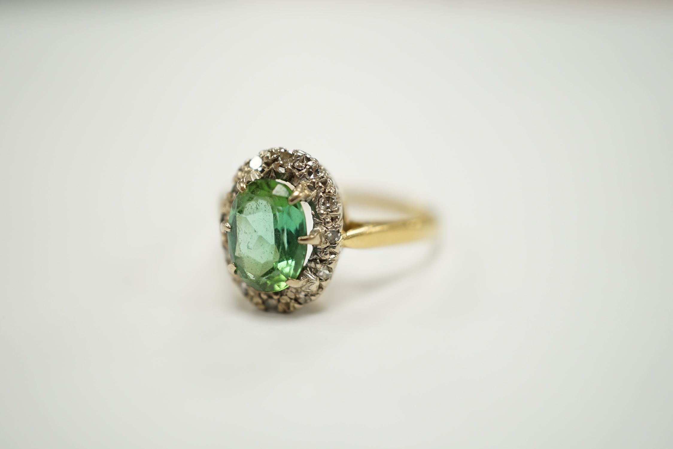 A modern 18ct gold, green tourmaline and diamond set oval cluster ring, size O/P, gross weight 3.5 grams.